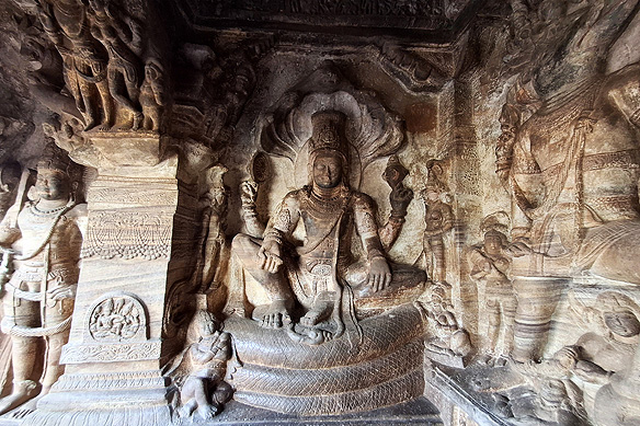 An inscription dates Cave 3, dedicated to Maha Vishnu, to 578 CE. Maha Vishnu is seen seated here on a seven-headed mythical serpent, flanked by an eight-armed Vishnu and Varaha, Vishnu's 3rd avatar.