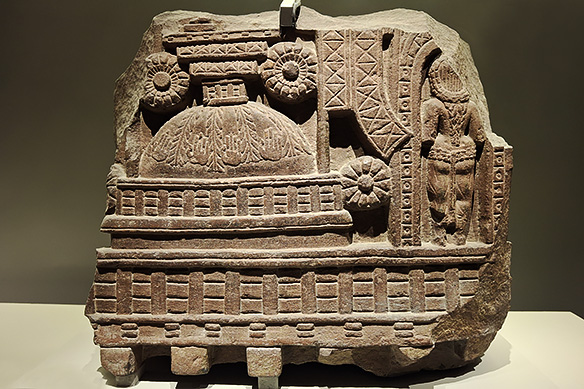 A female devotee is seen entering the stupa for worship. The circular dome is crowned by a harmika and flanked by a full-blown lotus. 2nd Century BCE, Bharhut, Madhya Pradesh.