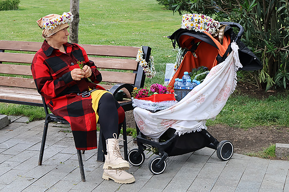 Woman selling coronets and water bottles to tourists at Rike Park.